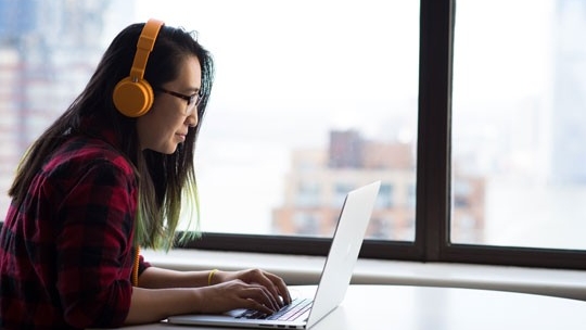 Student working on her laptop wearing headphones.