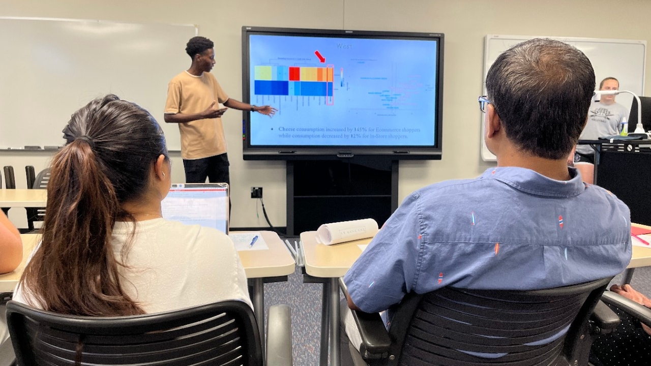 NKU undergraduate student practices their research presentation to fellow members of the research team in a classroom setting.