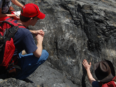 NKU Geology nealing on a giant rock while an instructor discusses formations.