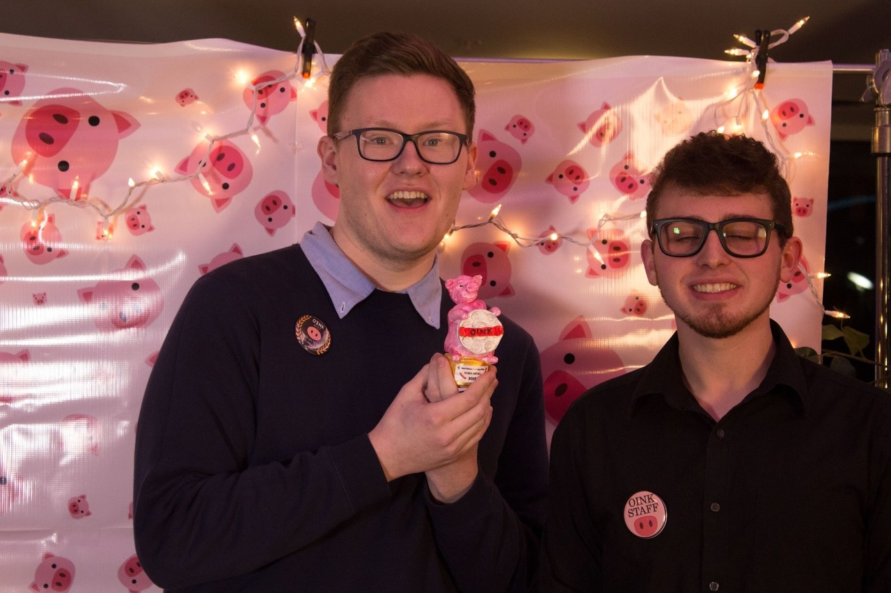 Image of two male OINK film festival participants holding a trophy.