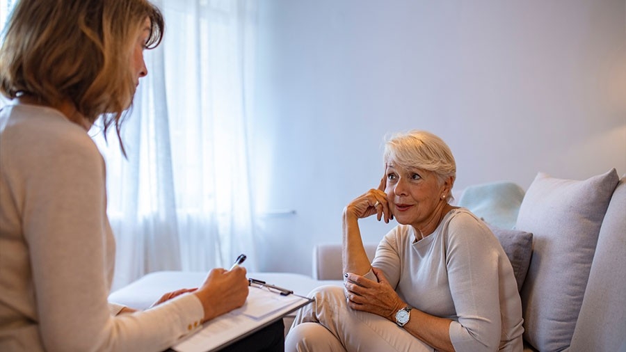 A younger woman takes notes while speaking with an older woman